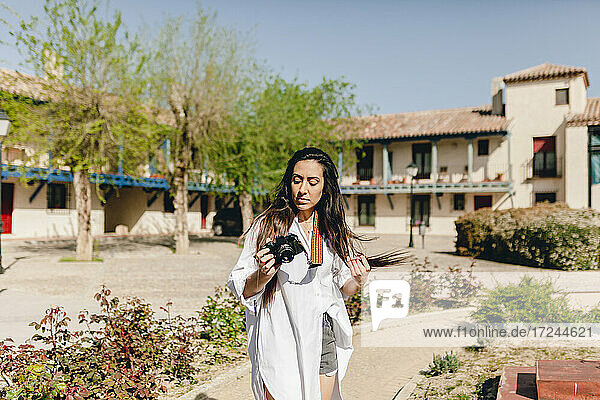 Weiblicher Tourist mit Kamera in einem Dorf an einem sonnigen Tag