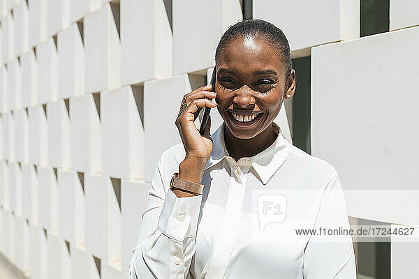 Glückliche Geschäftsfrau  die an einem sonnigen Tag mit ihrem Mobiltelefon spricht