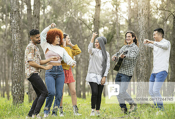 Männliche und weibliche Freunde tanzen und amüsieren sich im Wald