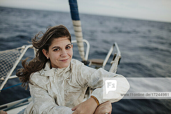 Lächelnde Frau sitzt auf einem Segelboot im Urlaub