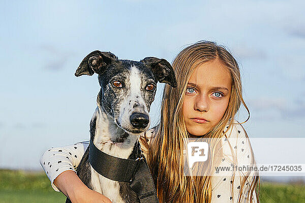 Blond girl with greyhound looking away