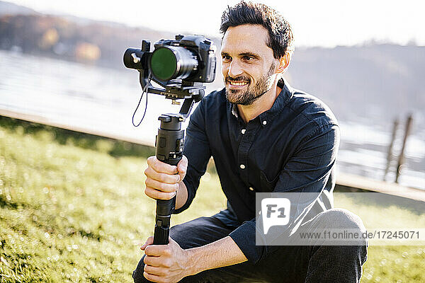 Handsome man holding gimbal looking through camera on sunny day