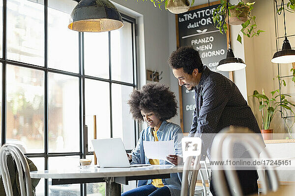 Geschäftsfrau mit Laptop und männlichem Kollegen bei der Arbeit im Café