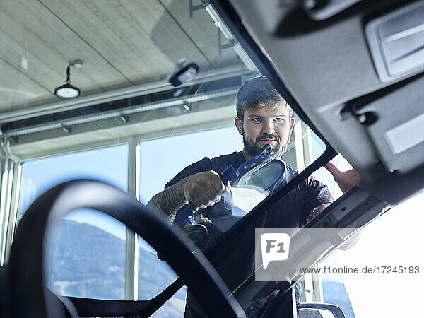 Ein Mechaniker reinigt die Windschutzscheibe eines Autos in einer Werkstatt