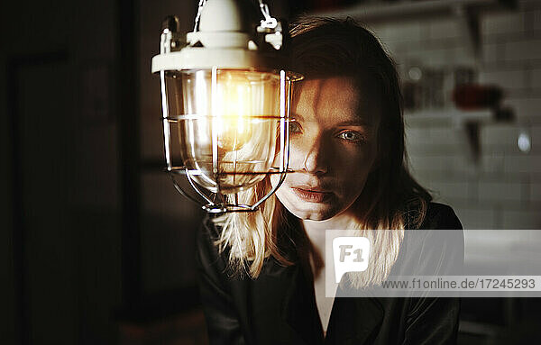 Sad woman staring behind electric lamp at home