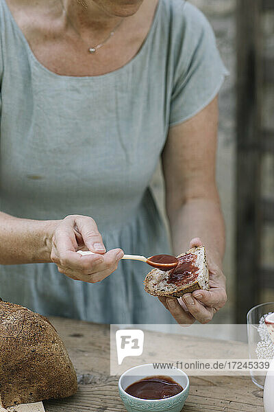 Reife Frau trägt Soße auf Brot im Hinterhof auf