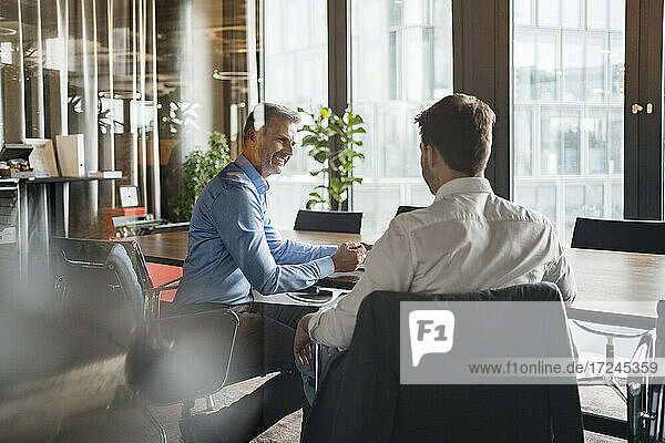 Smiling male entrepreneur in meeting with colleague at board room