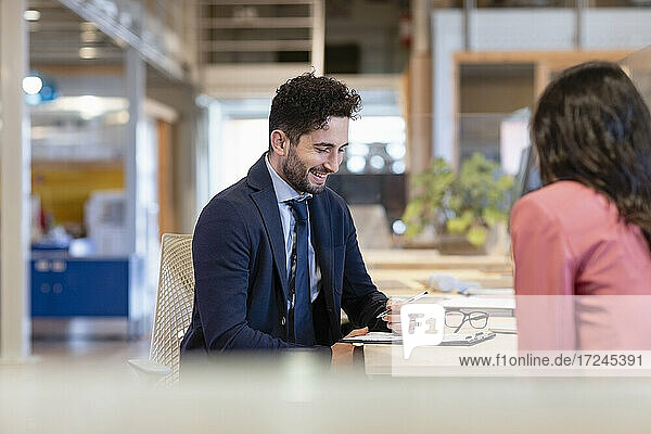 Lächelnder Geschäftsmann bei der Vertragsunterzeichnung in einem Coworking-Büro