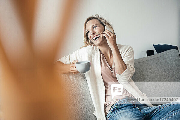 Fröhliche Frau spricht zu Hause am Telefon