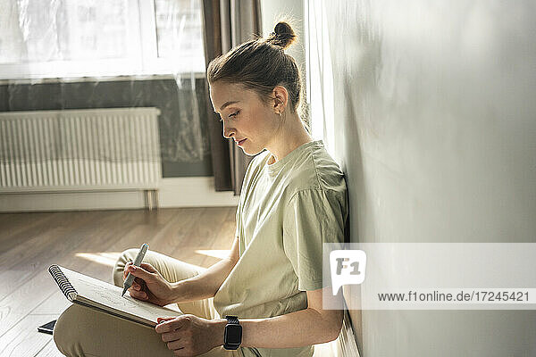 Junge Frau zeichnet zu Hause auf einem Notizblock
