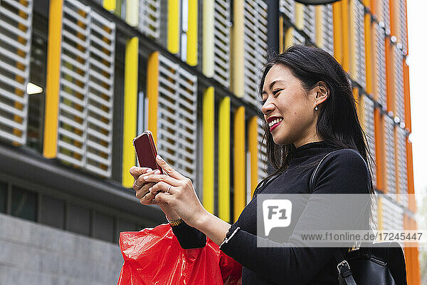Lächelnde Frau mit Rucksack und Mobiltelefon