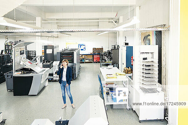 Businesswoman talking on mobile phone in printing press industry