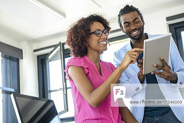 Smiling male and female professional using digital tablet at office