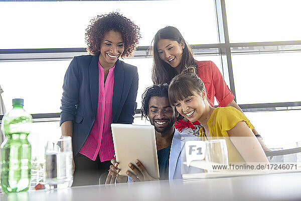 Junge männliche und weibliche Kollegen nutzen ein digitales Tablet im Büro