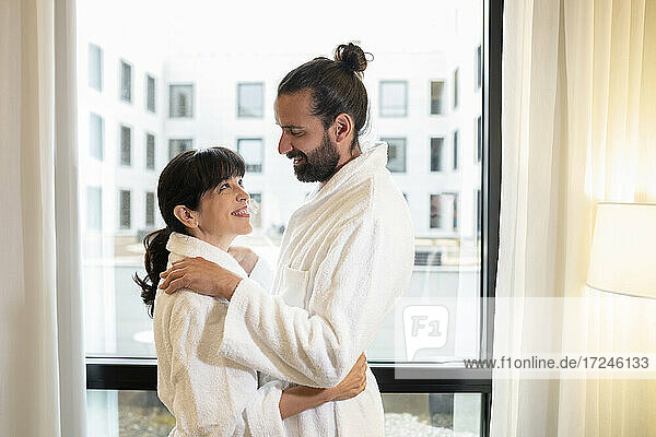 Mature couple wearing bathrobes embracing at hotel suite