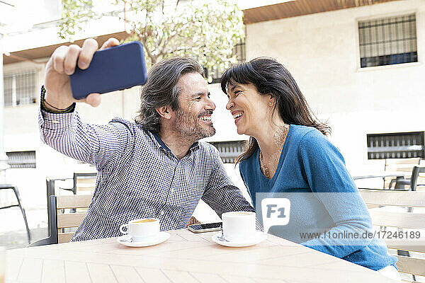 Lächelndes reifes Paar nimmt Selfie durch Handy auf Terrasse