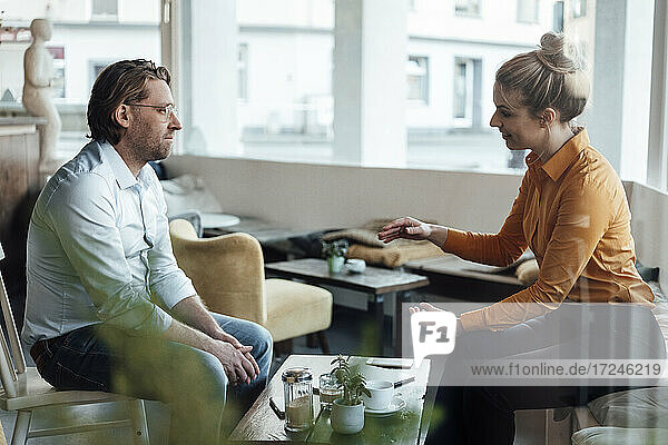 Mid adult businesswoman discussing with colleague at coffee shop