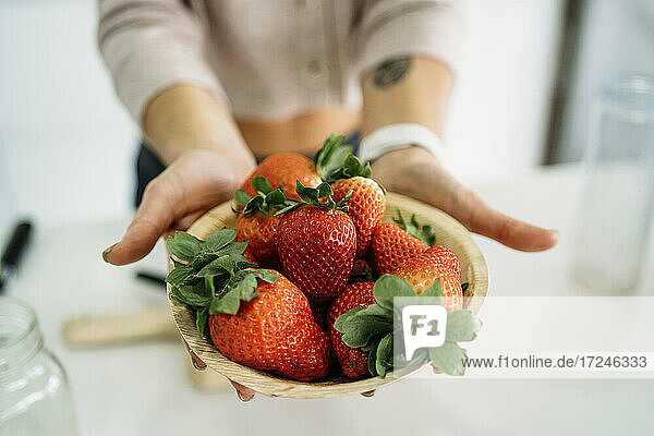 Frau hält frische Erdbeeren in einer Schale zu Hause