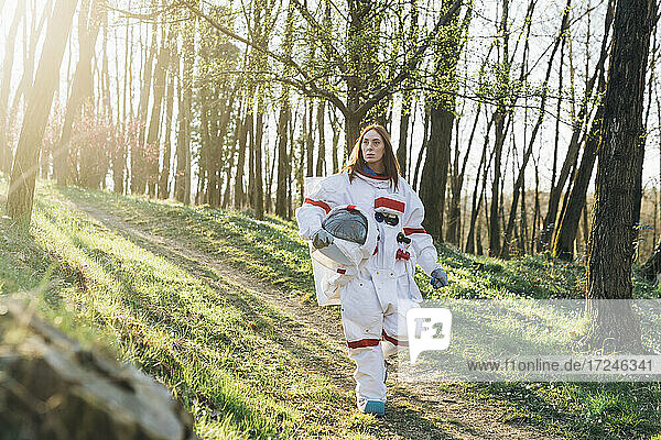 Junge Astronautin mit Weltraumhelm beim Gehen auf einem Feldweg