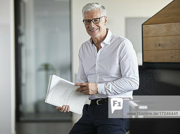 Unternehmer hält Papier und lächelt im Büro