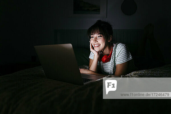 Lächelnde Frau mit Laptop in der Dunkelkammer