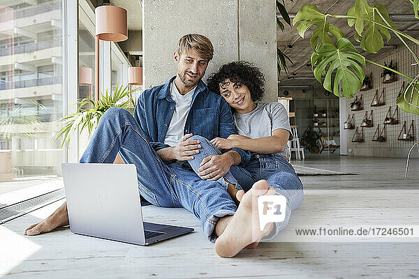 Woman with boyfriend looking at laptop in home apartment