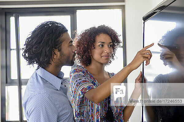 Unternehmerin beim Brainstorming mit einem männlichen Kollegen auf einem digitalen Bildschirm im Büro