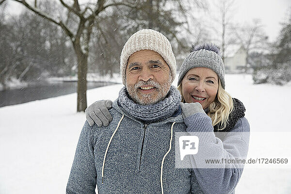 Lächelnde Frau in warmer Kleidung steht mit Mann im Park