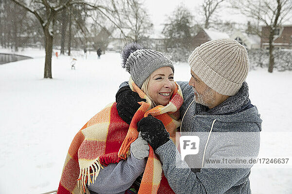 Man wrapping woman with blanket during winter