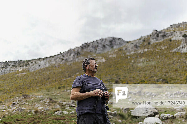 Senior man standing with binoculars on mountain