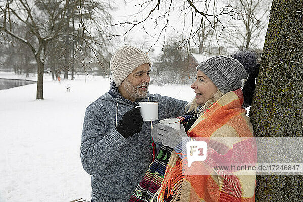 Senior couple talking while holding mug during winter