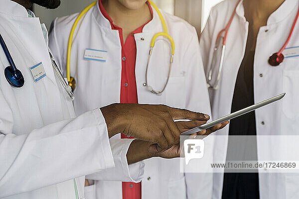 Männlicher Arzt benutzt digitales Tablet von weiblichen Kollegen im Krankenhaus