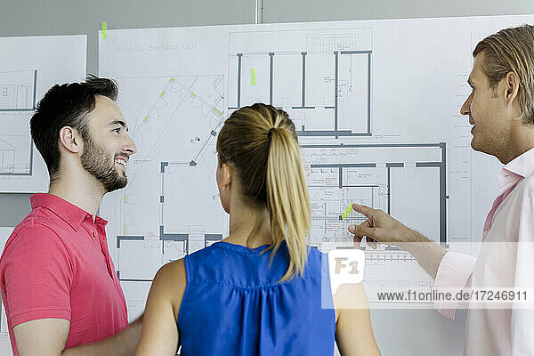 Male design professional explaining technical drawing to colleagues in office