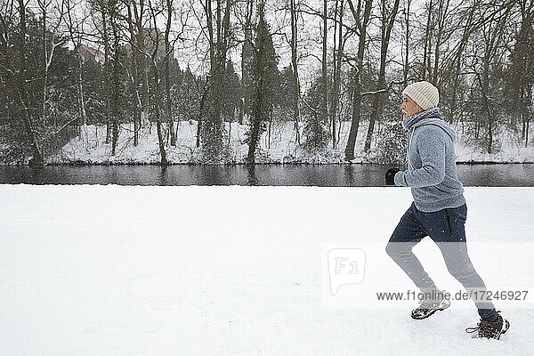 Mann läuft im Winter auf Schnee im Park