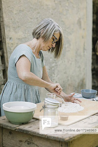 Mature woman preparing bread at back yard