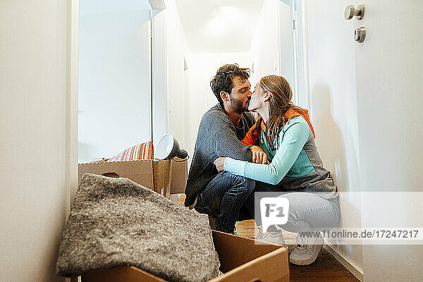 Affectionate couple kissing by box at home