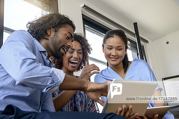 Internationale Studentinnen und Studenten lächeln bei der Nutzung eines digitalen Tablets in der Universität