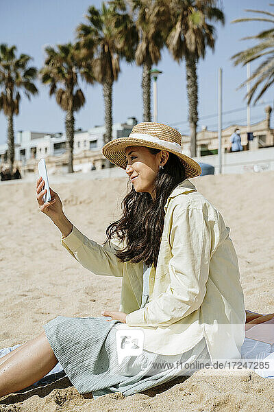 Frau  die ein Selfie macht  während sie am Strand sitzt