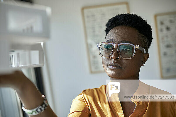 Female architect wearing eyeglasses holding model at office