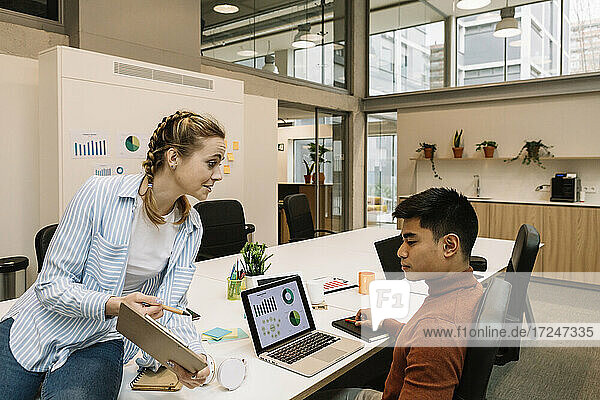 Businesswoman discussing strategy with male colleague at coworking office
