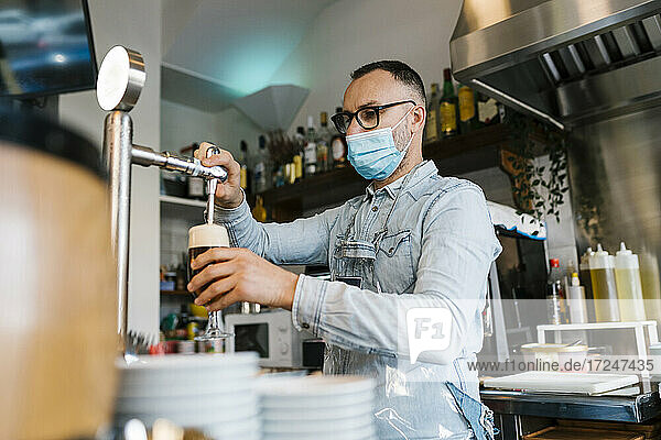 Kellner  der in einer Bar während einer Pandemie Bier in Gläser füllt