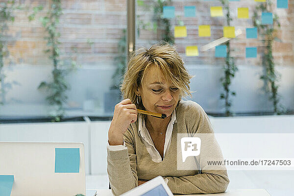 Nachdenkliche Geschäftsfrau sitzt am Schreibtisch in einem Coworking-Büro