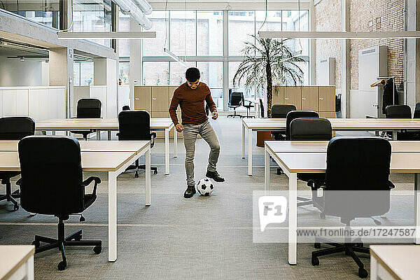 Junger Unternehmer spielt mit Fußball im Büro