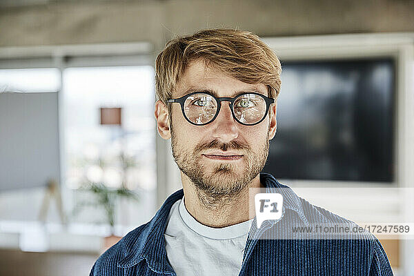 Blond man wearing eyeglasses contemplating at loft