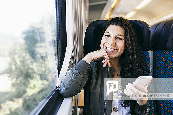Mittlere erwachsene Frau sitzend mit Hand am Kinn im Zug