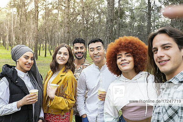 Multi-ethnische männliche und weibliche Freunde nehmen Selfie beim Genießen im Wald