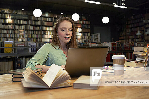 Schöne Frau  die einen Laptop benutzt und in einer Bibliothek studiert