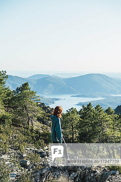 Junge Frau betrachtet die Aussicht  während sie auf einem Berg steht