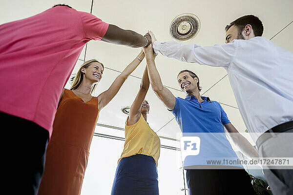 Male and female professionals team giving high-five to each other in office