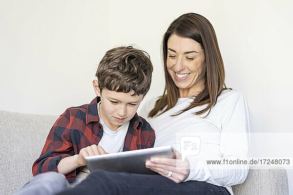 Junge benutzt digitales Tablet bei seiner Mutter zu Hause